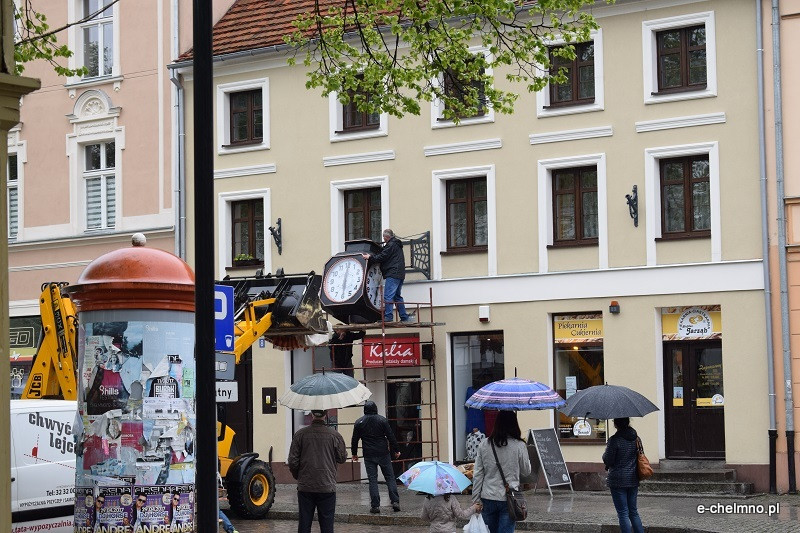 Montaż naprawionego zabytkowego zegara na kamienicy przy Rynku